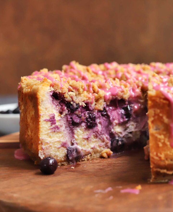 blueberry crumble cheesecake on cutting board with slice cut out showing creamy inside