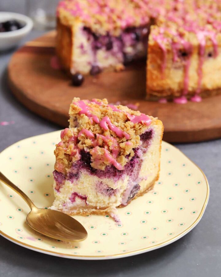 slice of blueberry crumble cheesecake on plate with bite and spoon
