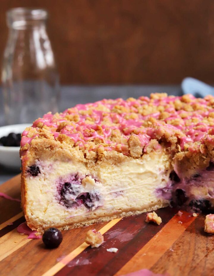 blueberry crumble cheesecake on cutting board with slice cut out showing creamy inside