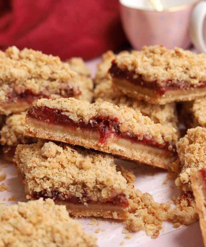 sliced strawberry crisp bars piled up on parchment paper