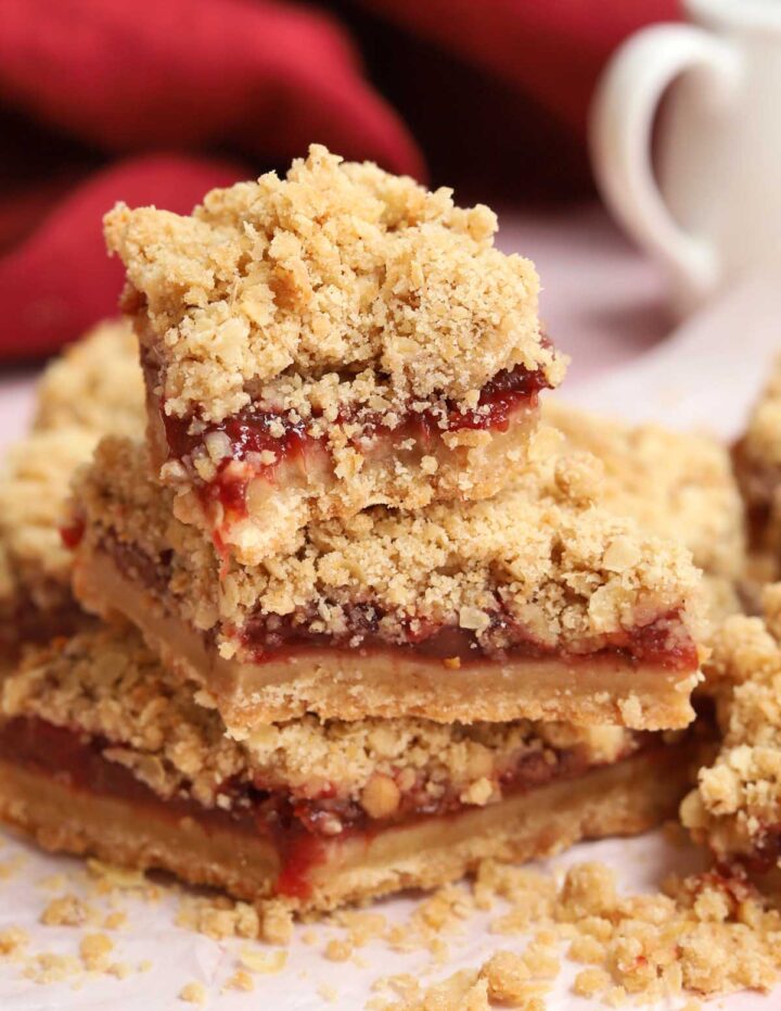 stack of strawberry crisp bars parchment paper with bite out of top bar