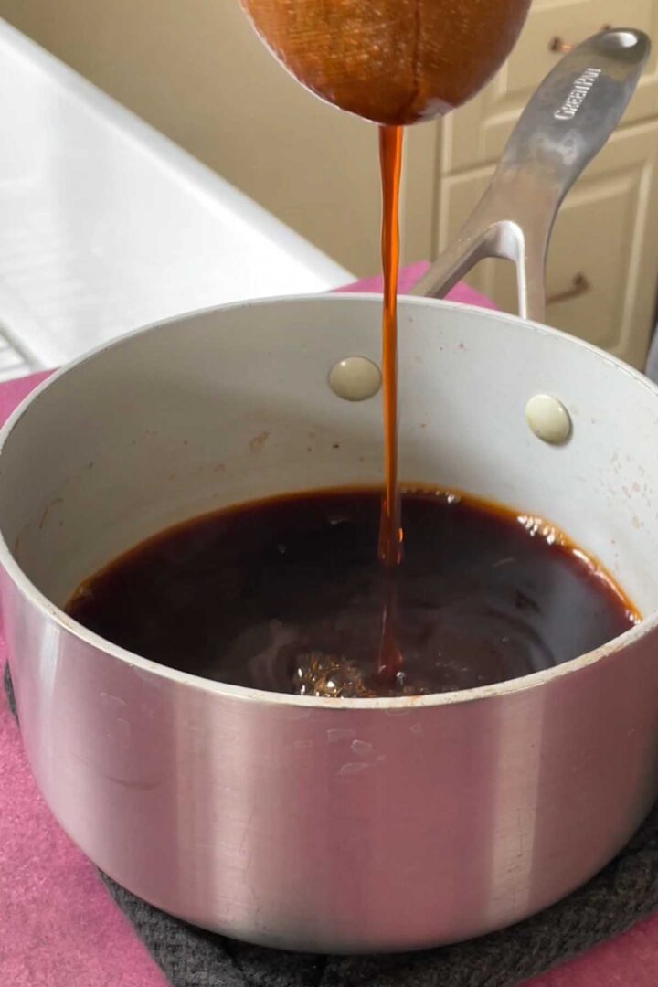straining Thai tea leaves through tea sock into saucepan