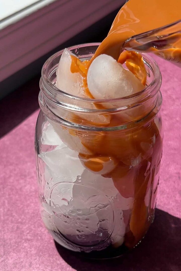 pouring Thai tea over ice into glass