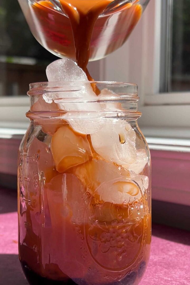 pouring Thai tea over ice into glass
