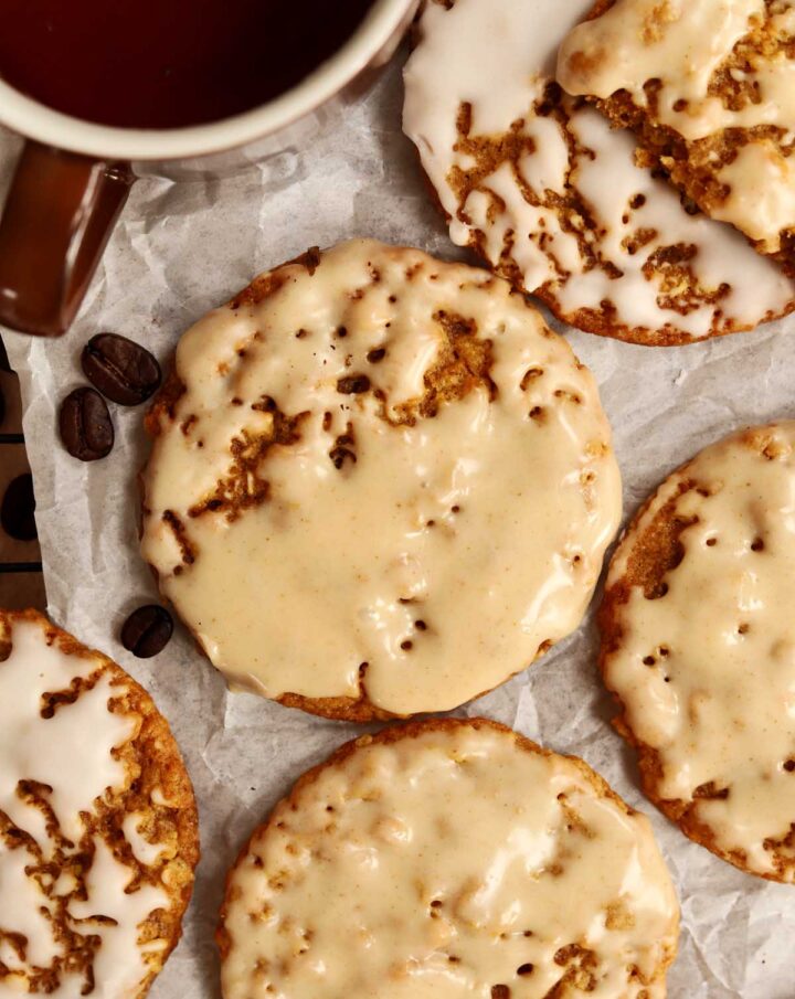 pumpkin spice latte iced oatmeal cookies on cooling rack with cup of coffee