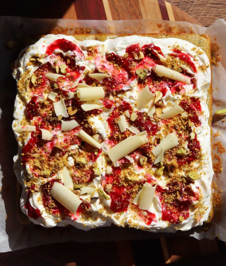 top view of raspberry pistachio cake on cutting board before slicing
