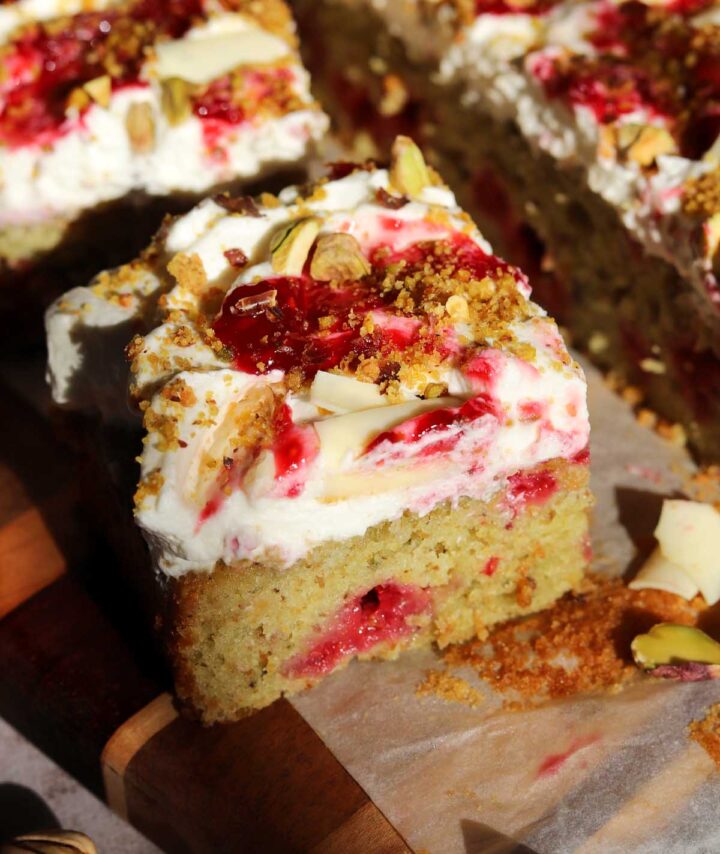 raspberry pistachio cake sliced on cutting board