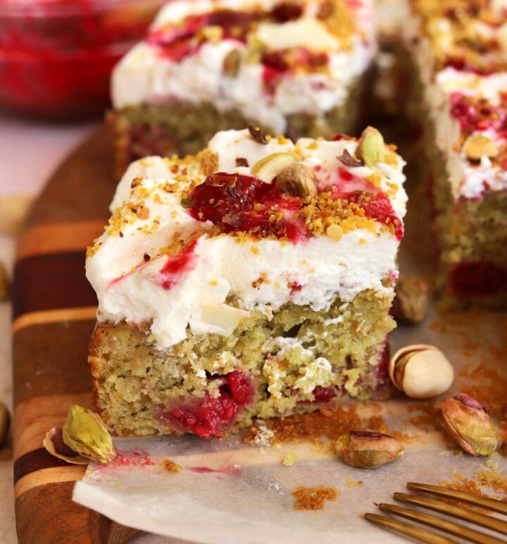 raspberry pistachio cake slice with bite on cutting board