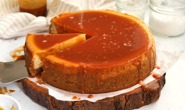 side view of sliced salted caramel cheesecake with slice coming out