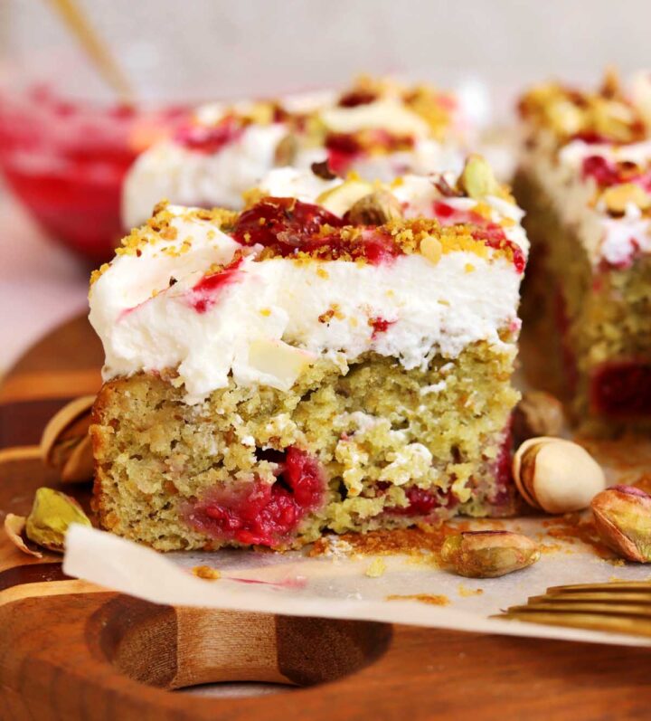 raspberry pistachio cake slice with bite on cutting board