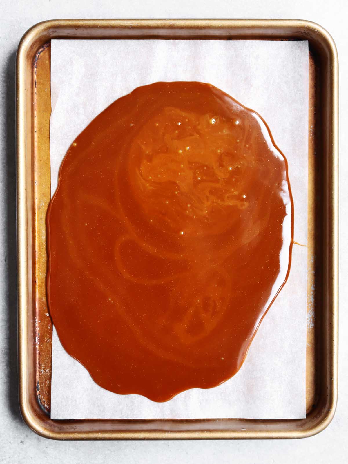 homemade toffee poured out on a lined baking sheet to set