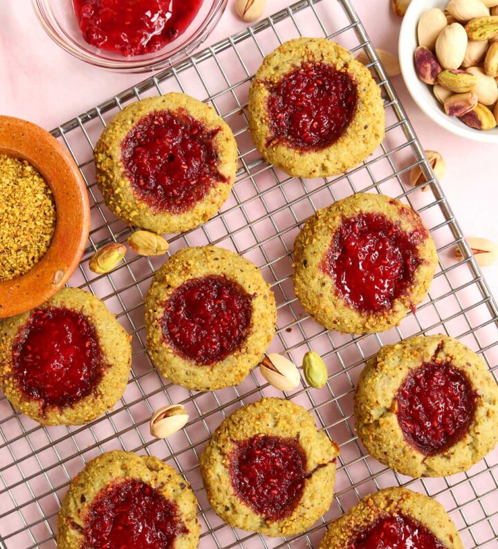 raspberry pistachio thumbprint cookies on cooling rack