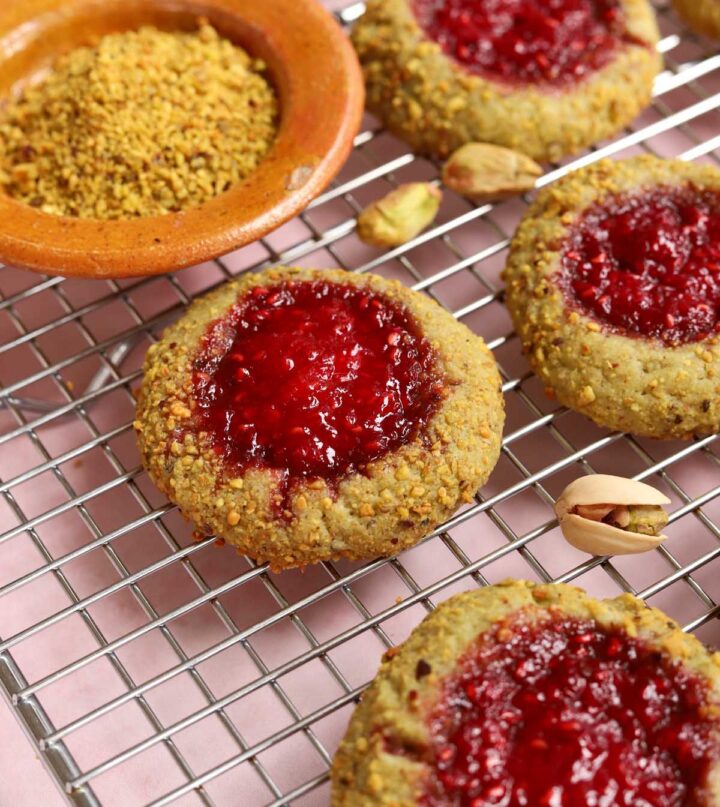 angle view of raspberry pistachio thumbprint cookies on cooling rack