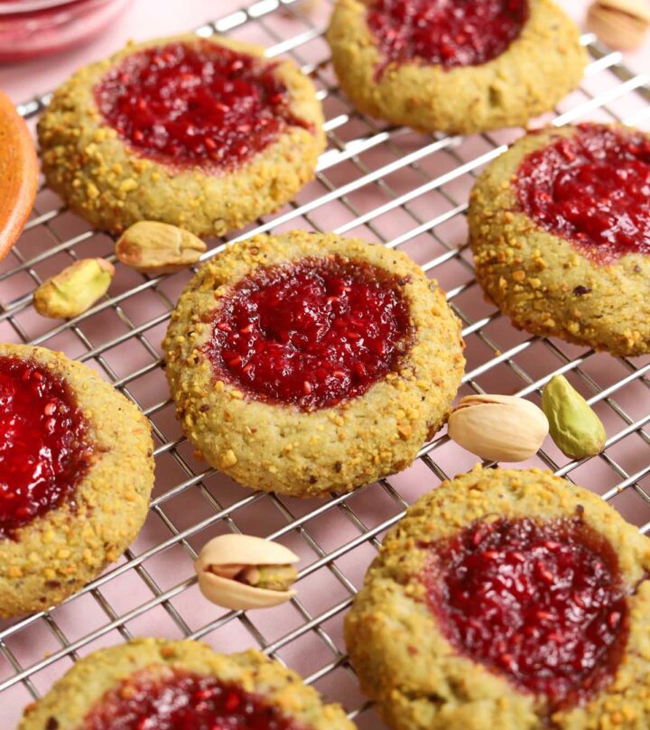 angle view of raspberry pistachio thumbprint cookies on cooling rack