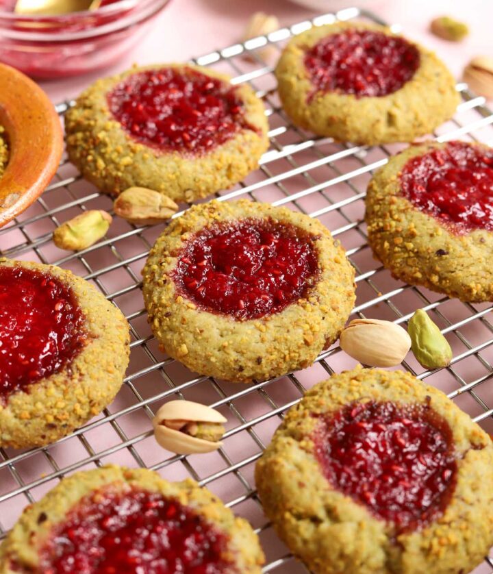 angle view of raspberry pistachio thumbprint cookies on cooling rack