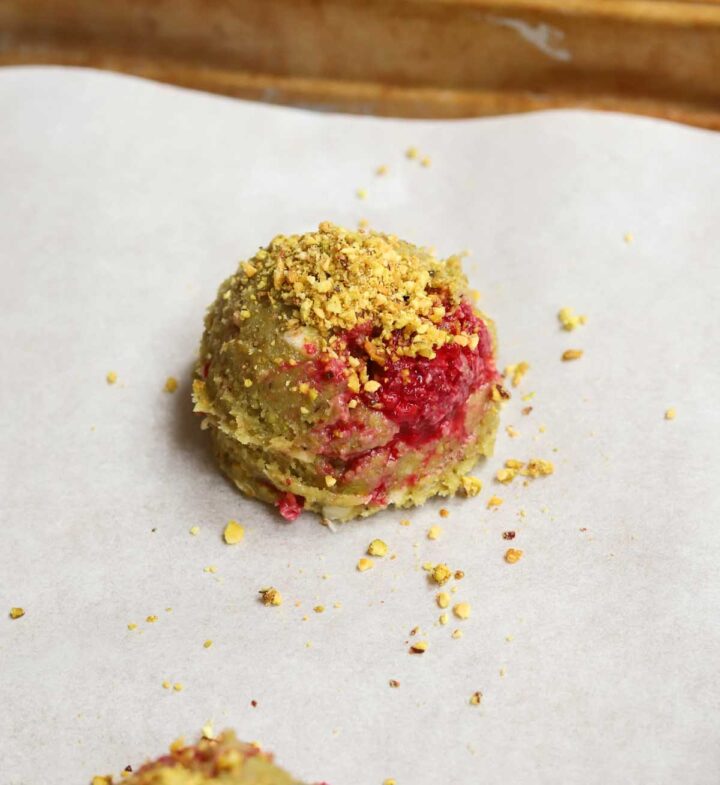 white chocolate raspberry pistachio cookie dough ball on baking sheet before baking
