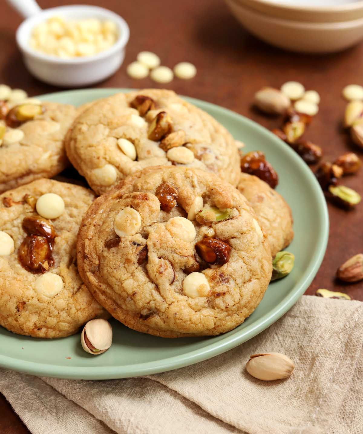 side view of caramelized pistachio brown butter white chocolate cookies on a plate