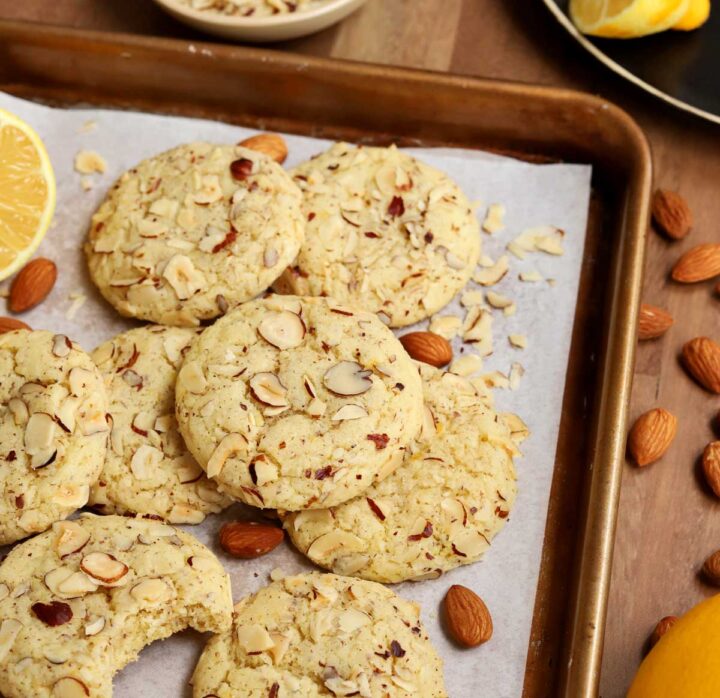 lemon almond cookies piled up on baking sheet