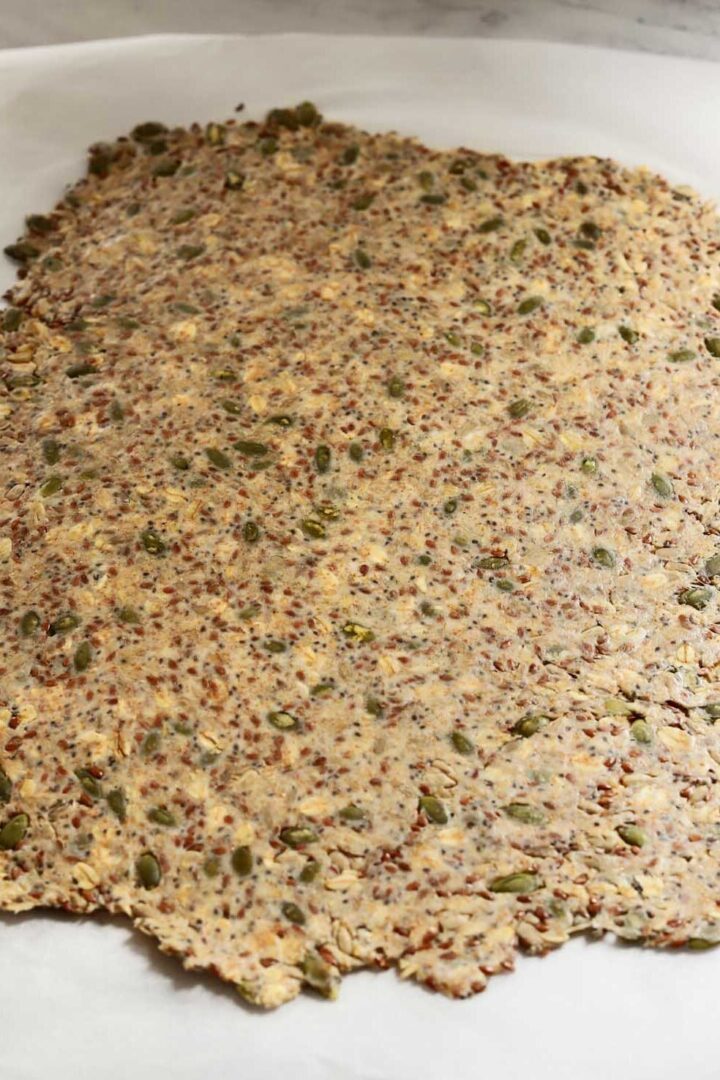 super seed cracker dough rolled out thinly on parchment