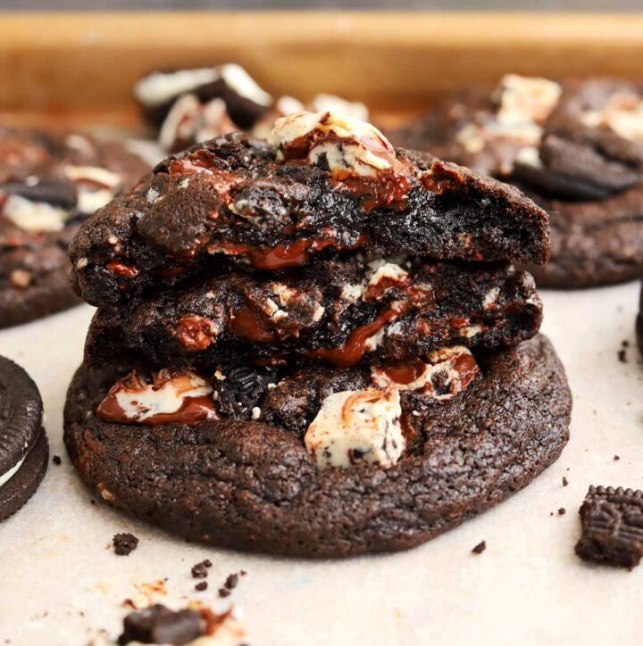 double chocolate cookies and cream cookies stacked with bite showing fudgy center
