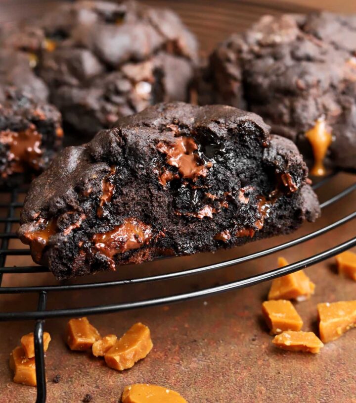 levain bakery coffee toffee cookies broken in half on a cooling rack showing fudgy interior