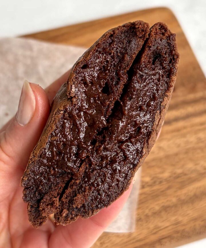 fudgy molten brownie cookie in hand split in half showing molten center