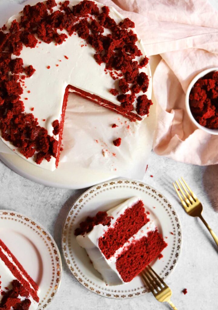 top view of sliced red velvet cake with a slice on a plate and fork on the side