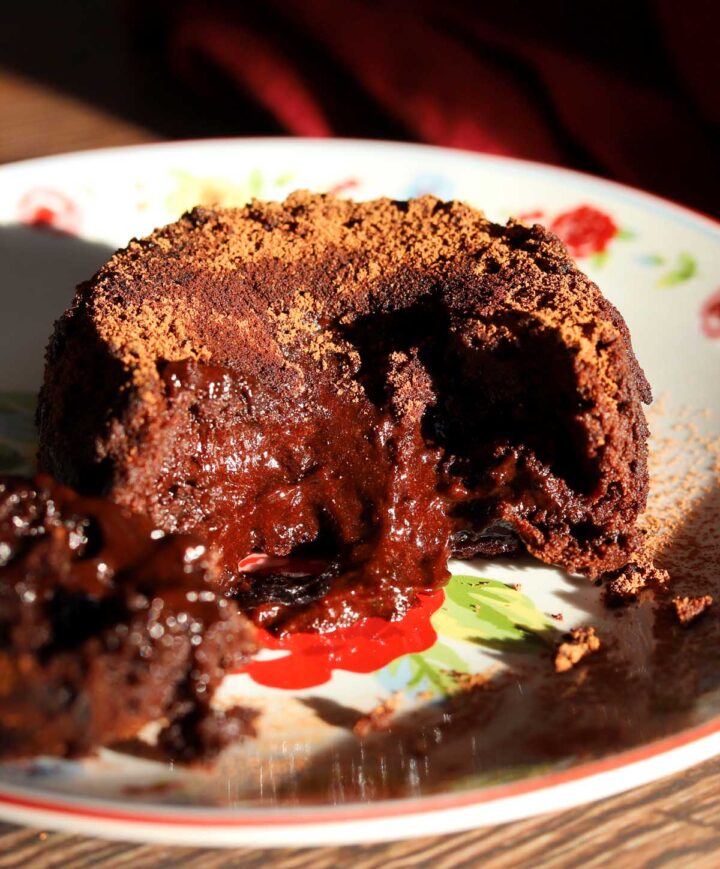 molten chocolate lava cake on a plate with spoon showing molten center flowing out