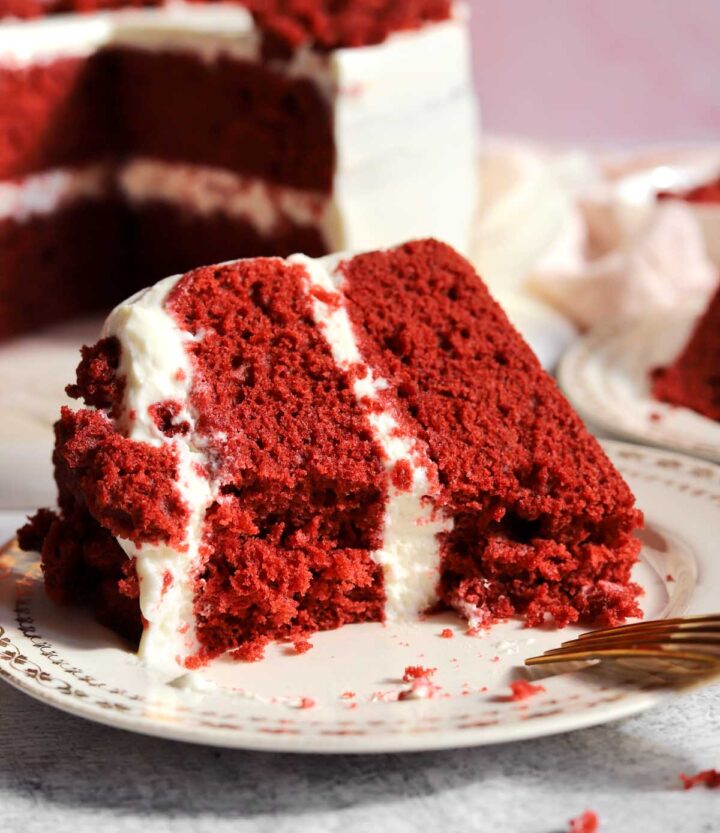 slice of red velvet cake on a plate with bite and a fork
