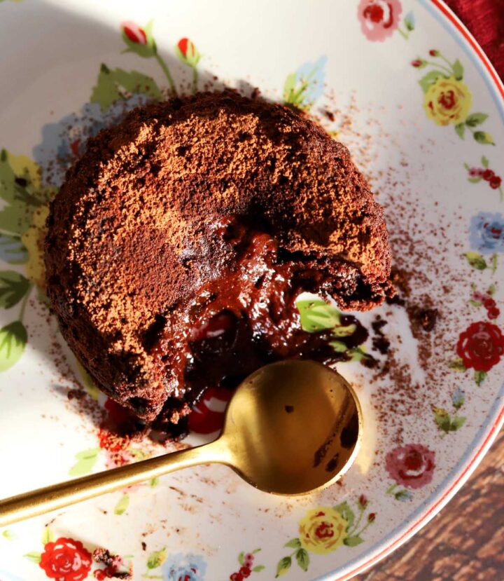 top view of molten chocolate lava cake on a plate with spoon showing molten center flowing out