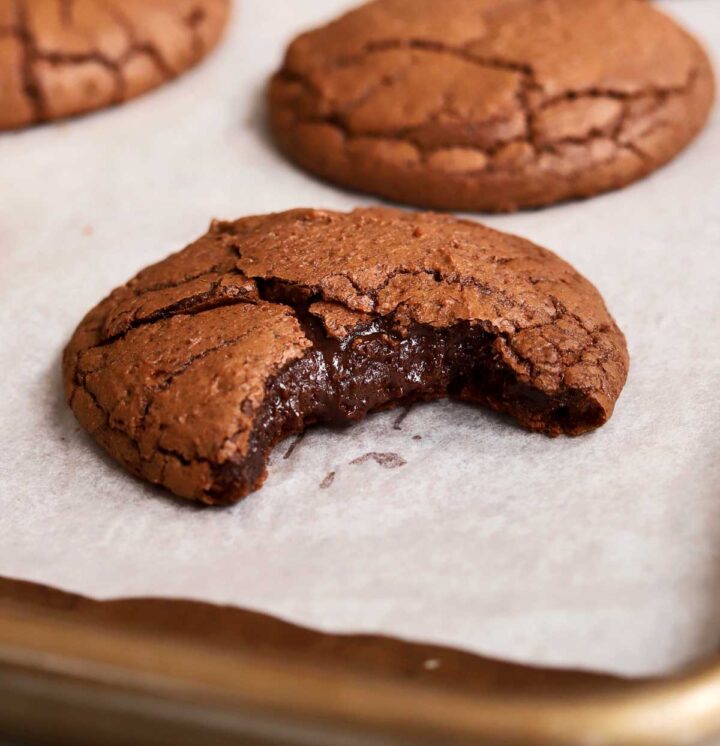 fudgy molten brownie cookie with bite showing molten center on baking sheet