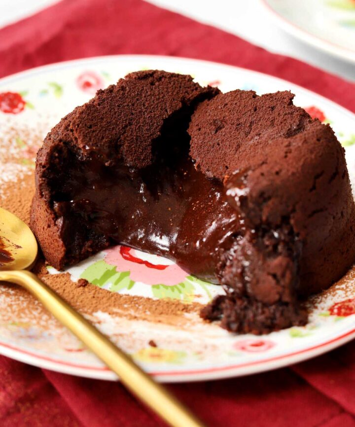 molten chocolate lava cake on a plate with spoon showing molten center flowing out