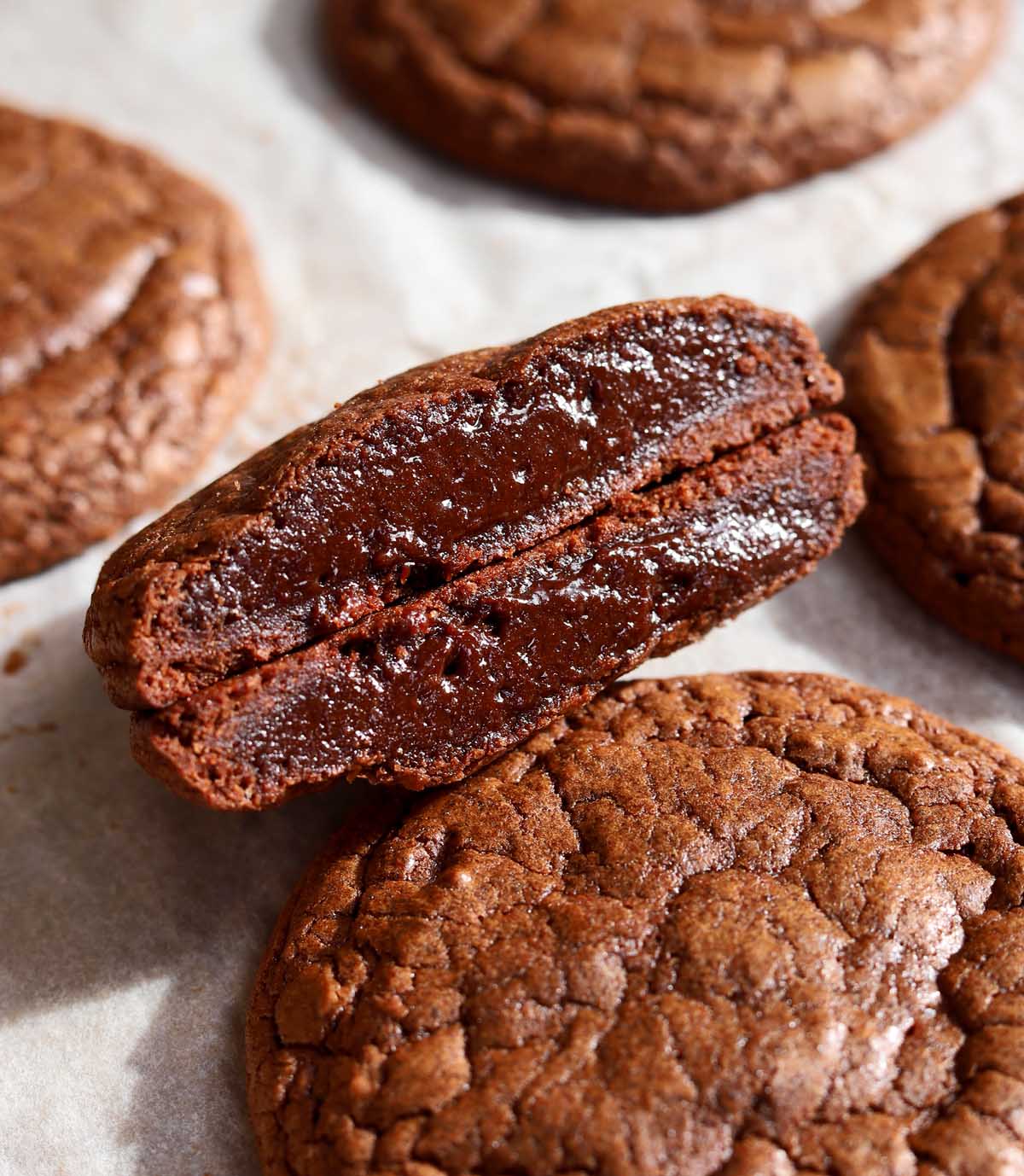 chocolate fondant cookie cut in half showing molten fudgy center on baking sheet