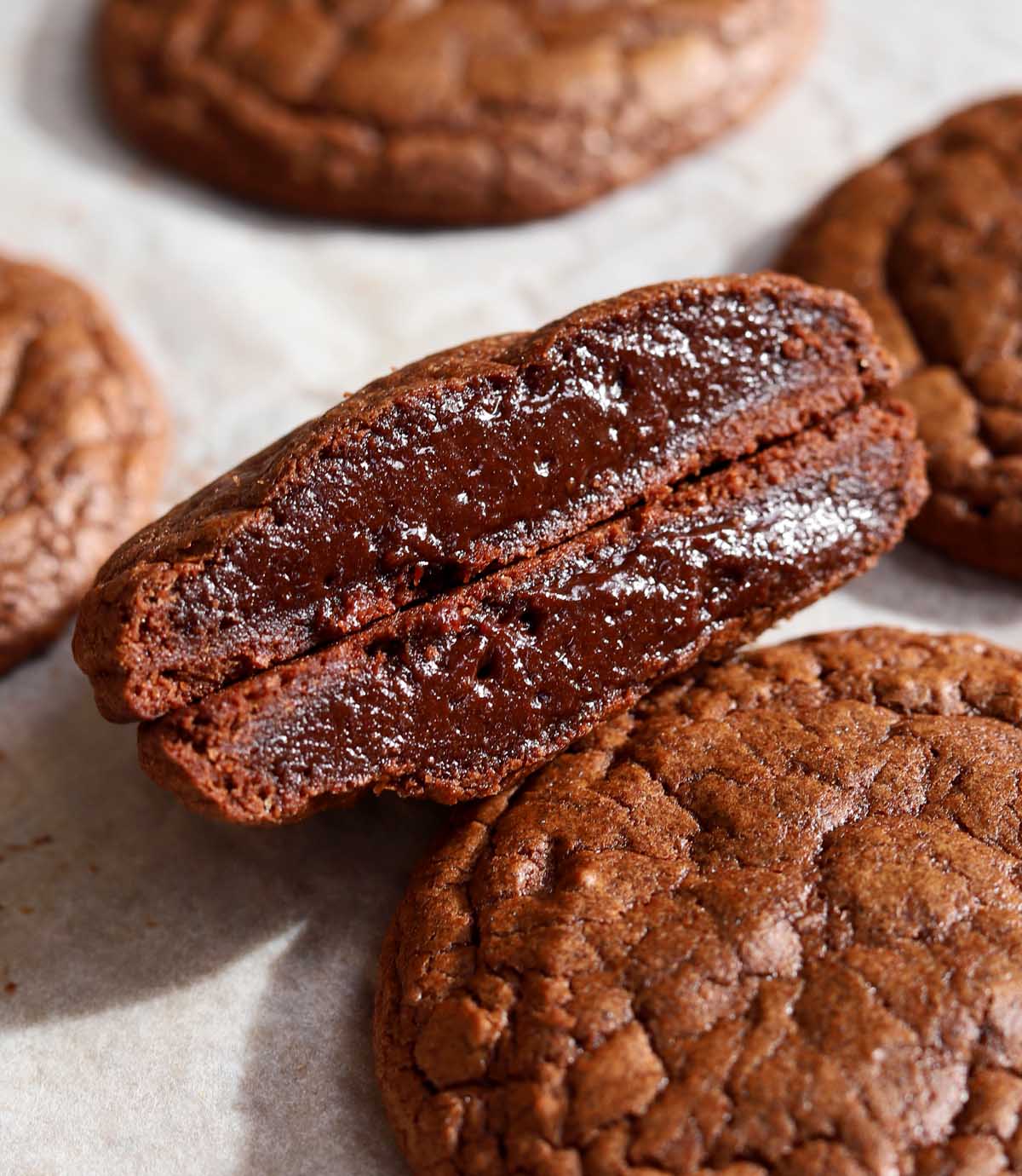 chocolate fondant cookie cut in half showing molten fudgy center on baking sheet