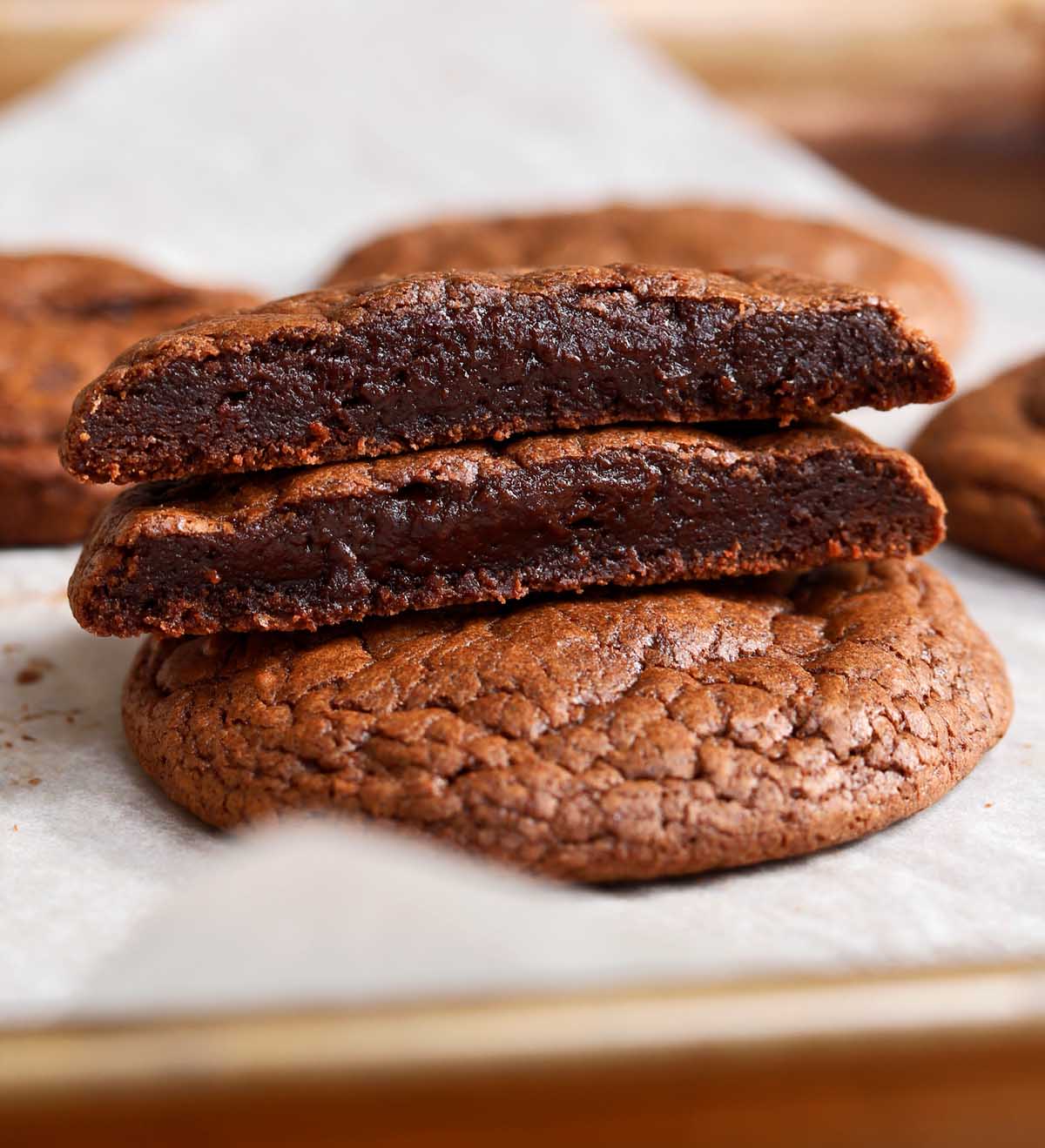 chocolate fondant cookie cut in half and stacked showing fudgy center on baking sheet
