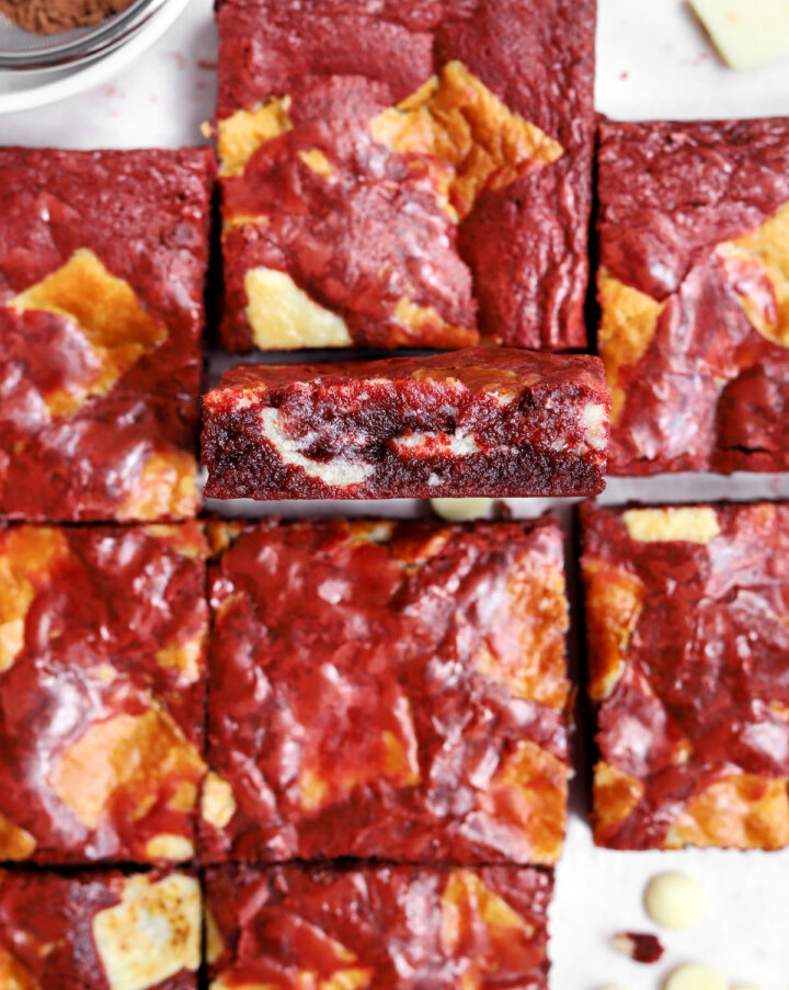 fudgy red velvet brownies sliced on parchment with a single square facing up showing fudgy center