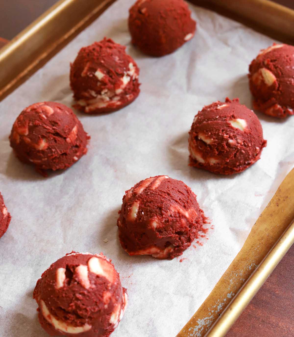 red velvet cookie dough on parchment lined baking sheet before baking