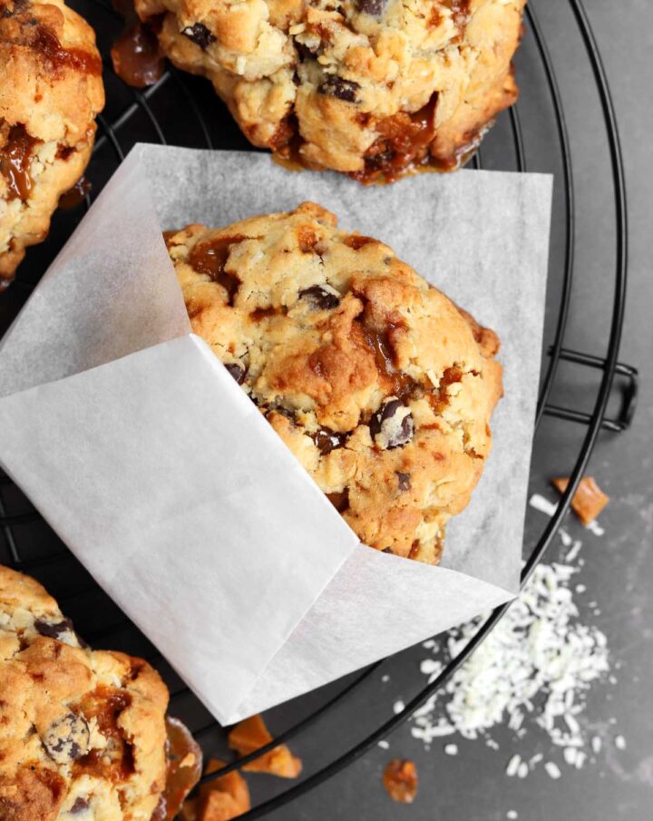 levain bakery caramel coconut cookie in paper sleeve on cooling rack