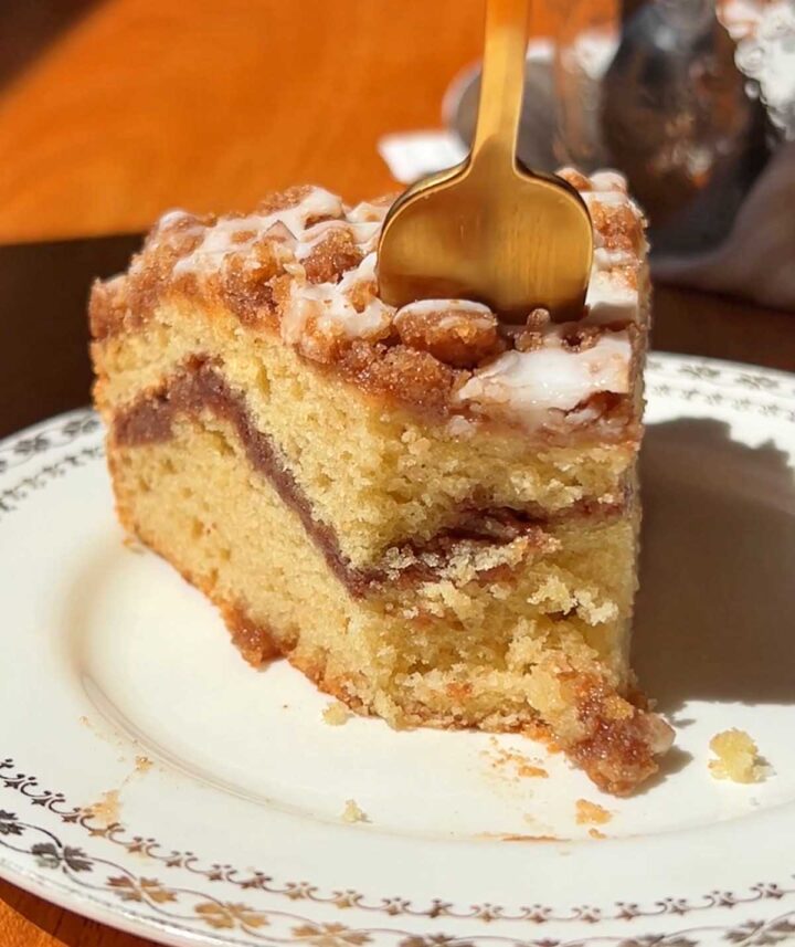slice of sour cream coffee cake on a plate with fork to take a bite