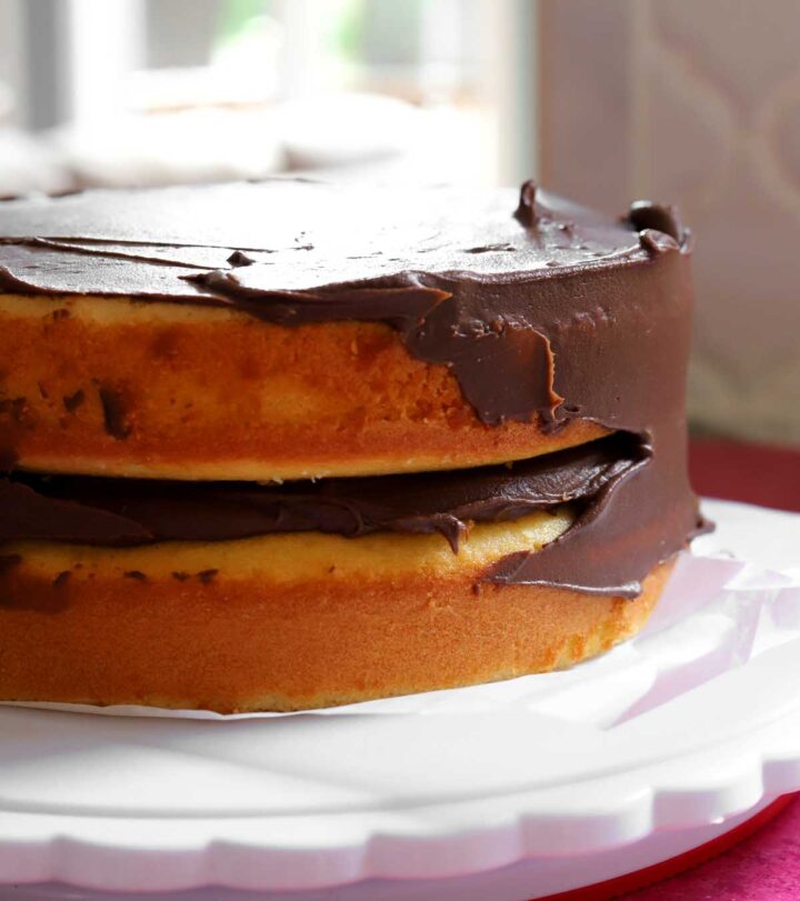 applying chocolate frosting on classic vanilla birthday cake layers