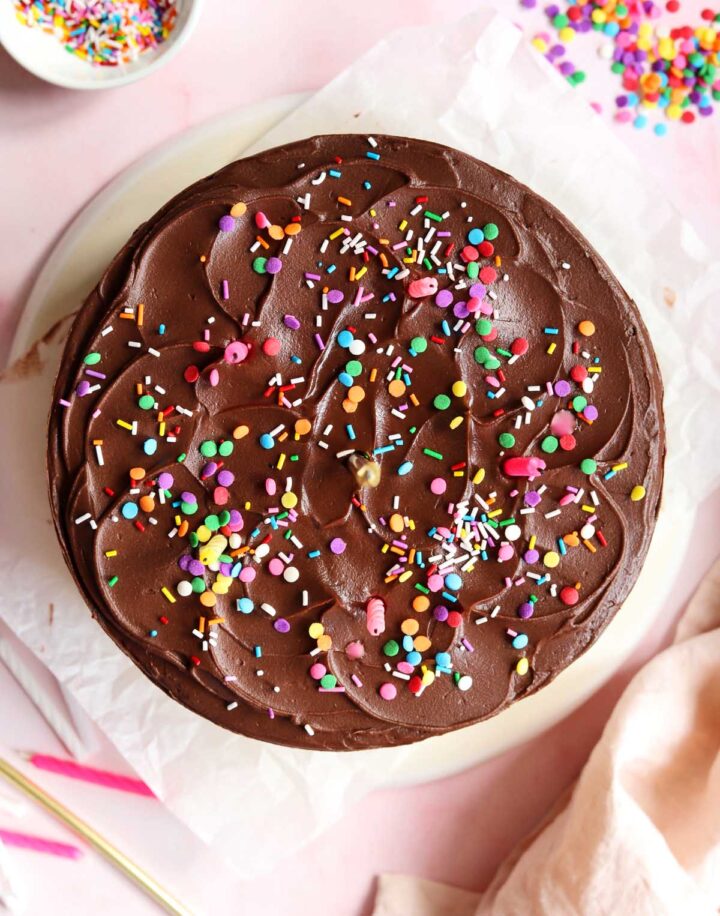top view of classic vanilla birthday cake  with chocolate frosting and sprinkles on serving plate