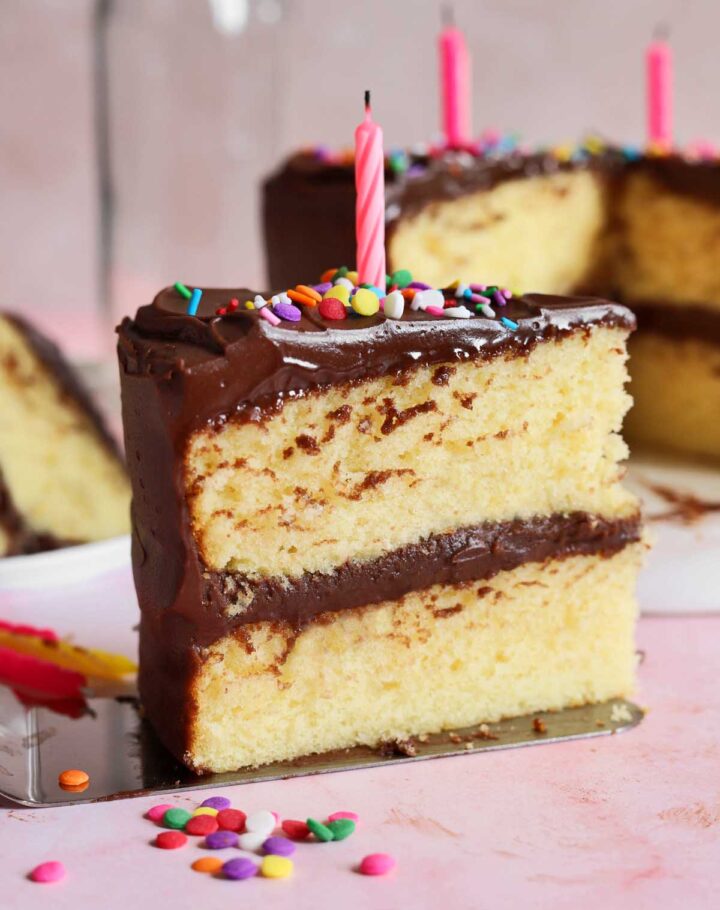 side view of slice of classic vanilla birthday cake on cake server