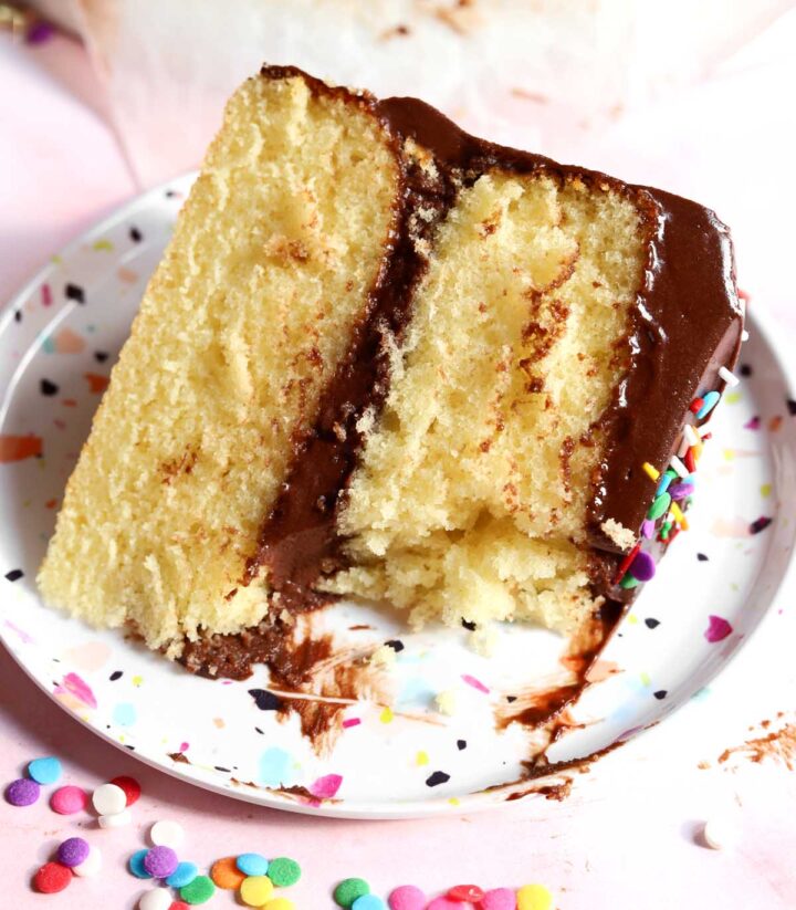 slice of classic vanilla birthday cake on plate with bite