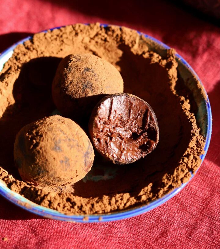 one ingredient chocolate water truffles with bite in bowl with cocoa powder