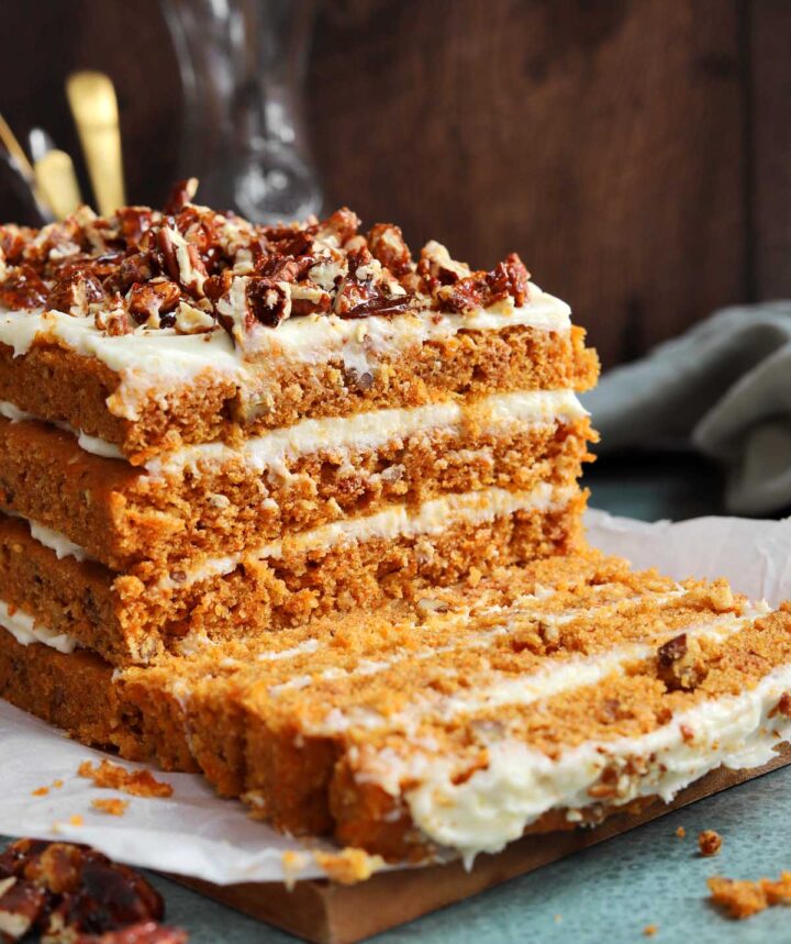 praline crunch carrot cake layer cake on a cutting board sliced showing the cross section of all 4 layers