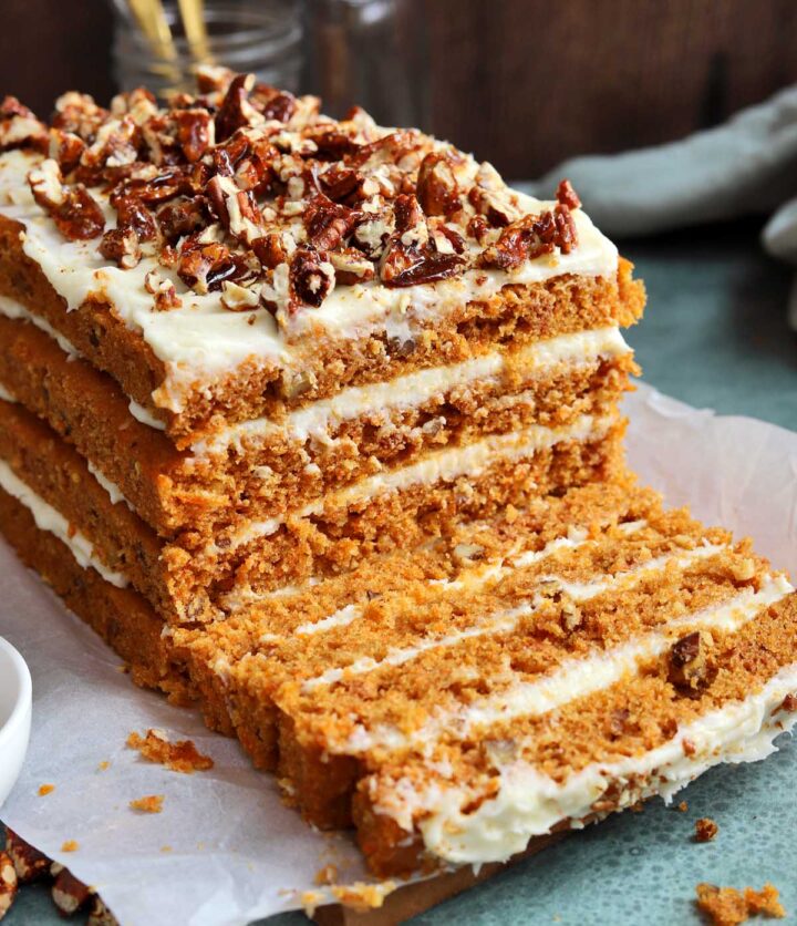 praline crunch carrot cake layer cake on a cutting board sliced showing the cross section of all 4 layers