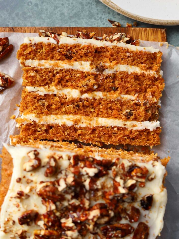 praline crunch carrot cake layer cake on a cutting board sliced showing the cross section of all 4 layers