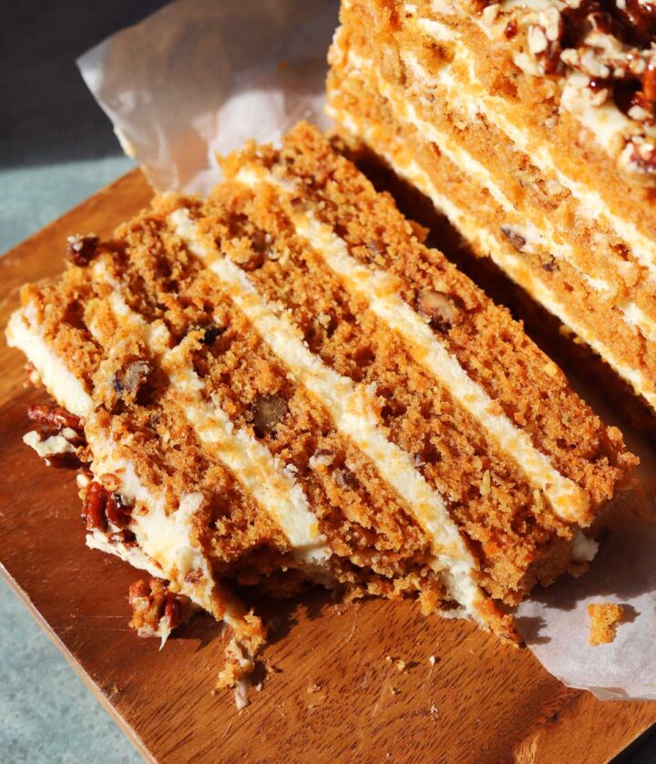 praline crunch carrot cake layer cake on a board with bite out of a slice