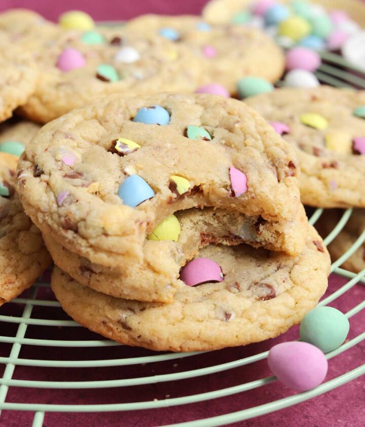 mini egg sugar cookies stacked on wire rack with bite