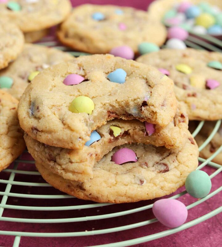 mini egg sugar cookies stacked on wire rack with bite
